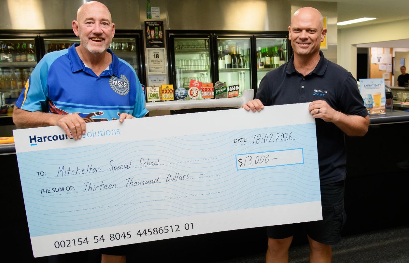 Harcourts Solutions Director Etienne Labuschagne presents a $13,000 cheque to Mitchelton Special School Principal Sheldon Hooper following the 2026 Harcourts Solutions Charity Golf Day.